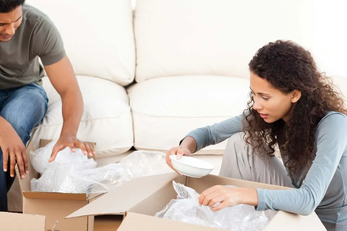 Couple carefully packing fragile items with bubble wrap before moving.