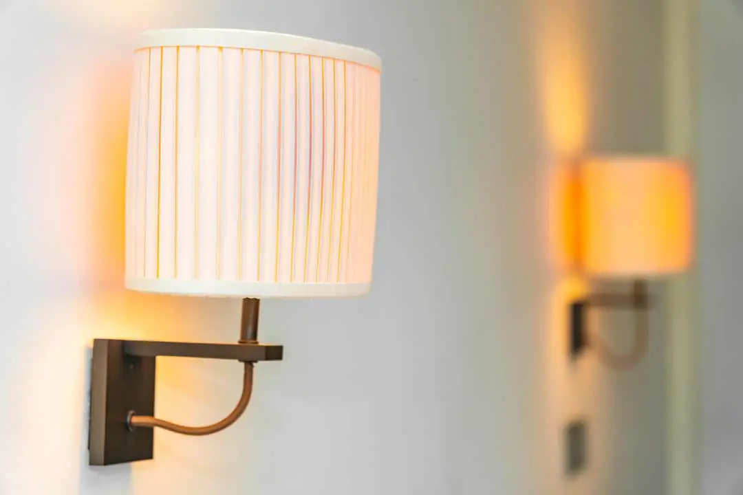 Close-up of a wall-mounted light fixture with a warm glow and fabric shade.