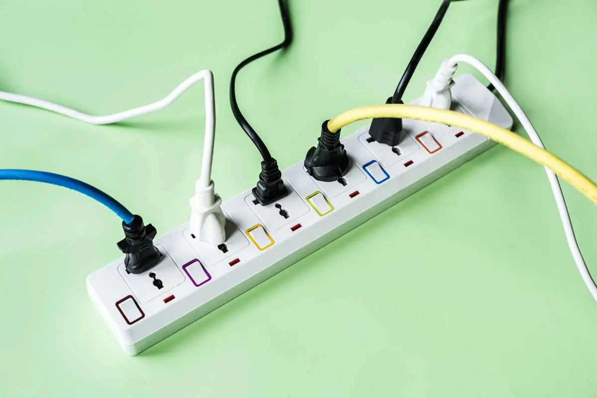 Power strip with various colored plugs connected on a green background.