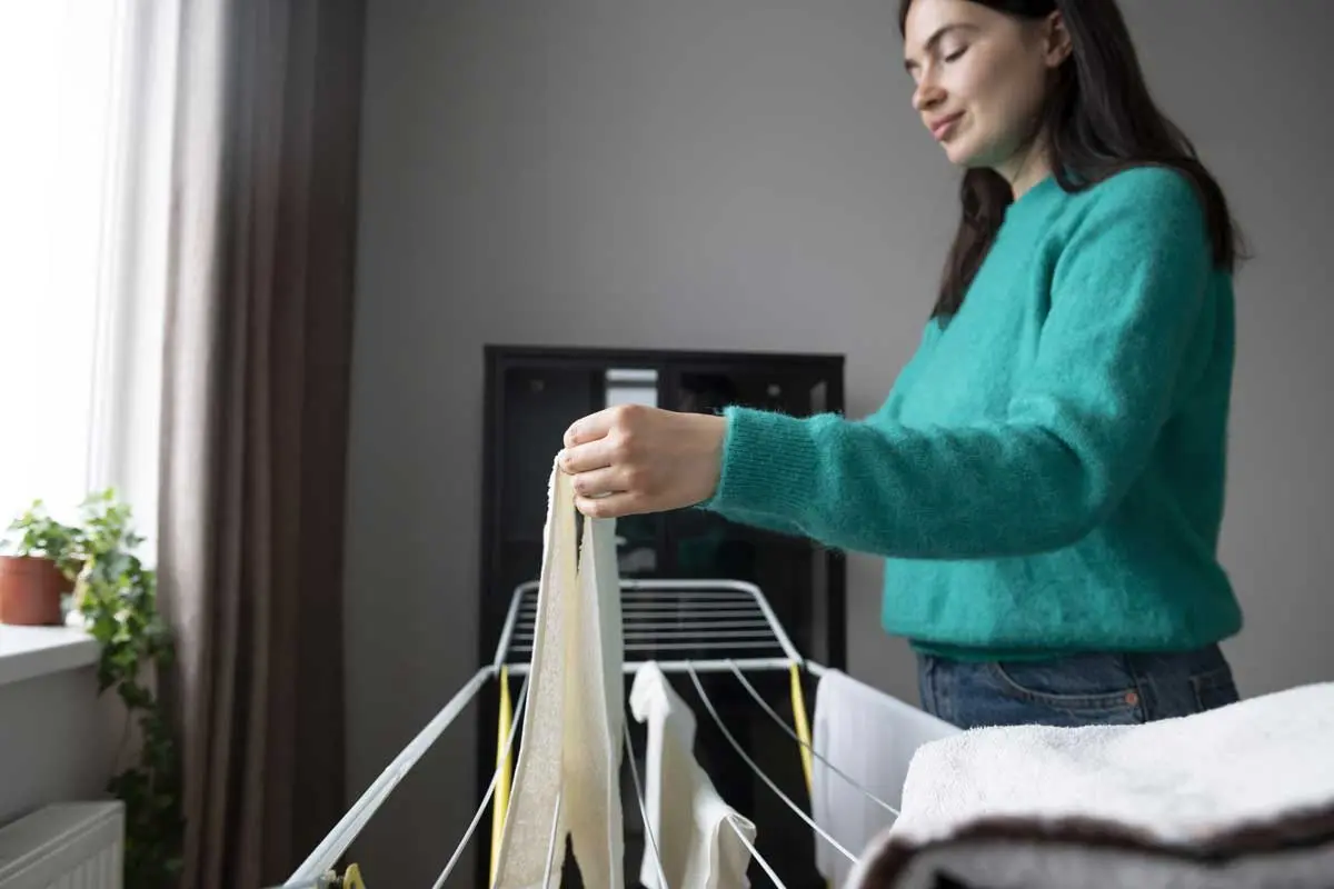 Woman hanging laundry on an indoor drying rack.