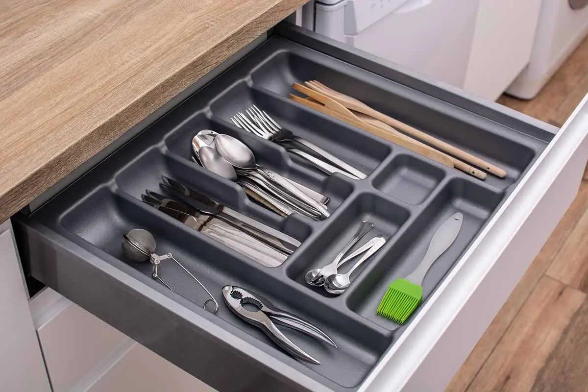 Neatly arranged kitchen drawer with cutlery and utensils in designated compartments for easy access and organization.