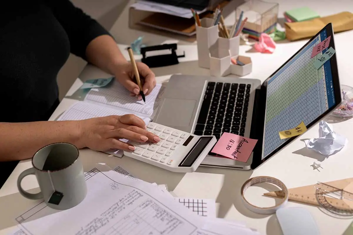 Organized workspace with calculator, laptop, and sticky notes arranged for efficient work.