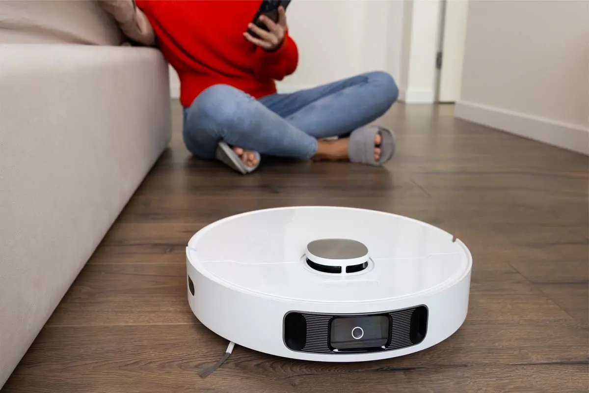 Robotic vacuum cleaner on floor with person nearby.