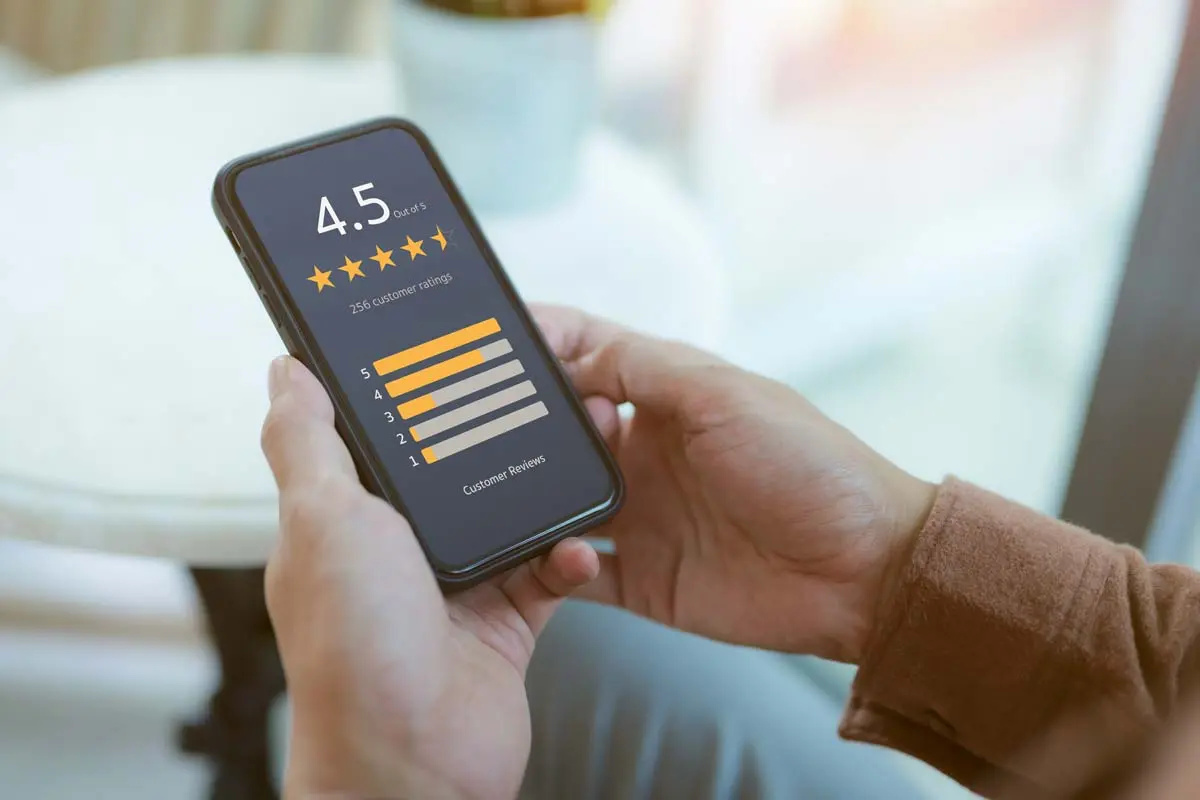 Close-up of hands holding a smartphone showing a 4.5-star customer review rating.