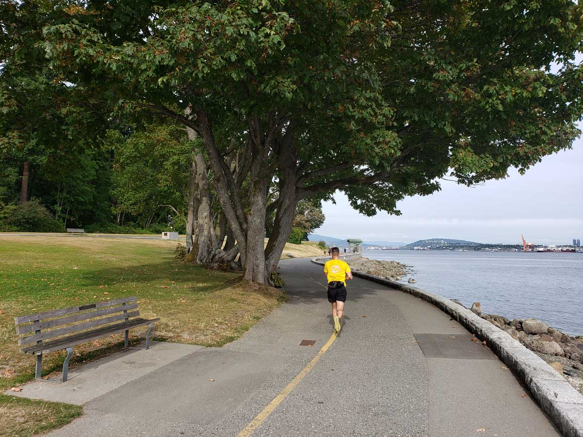 Runner jogging along the Stanley Park Seawall beside the water.
