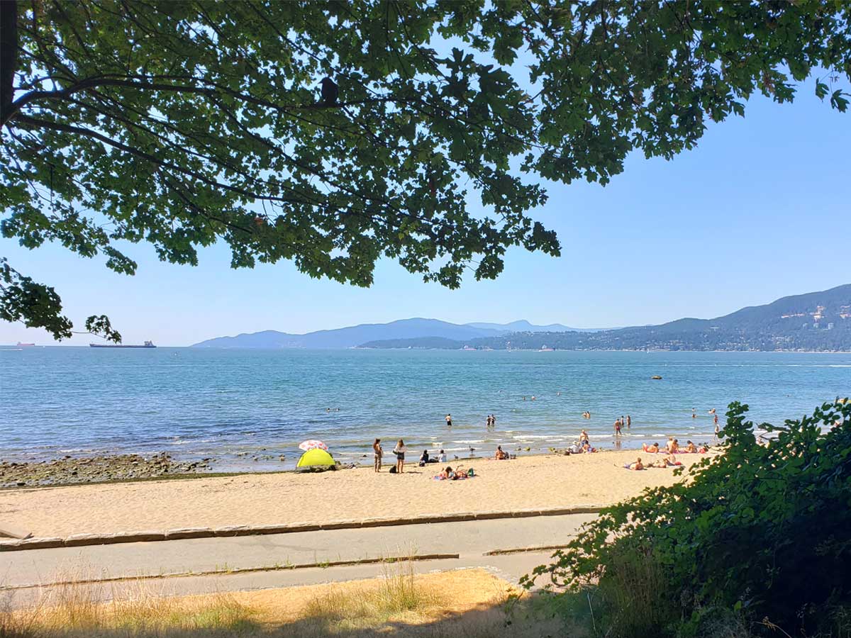 Third Beach in Stanley Park with people enjoying the sun and ocean.