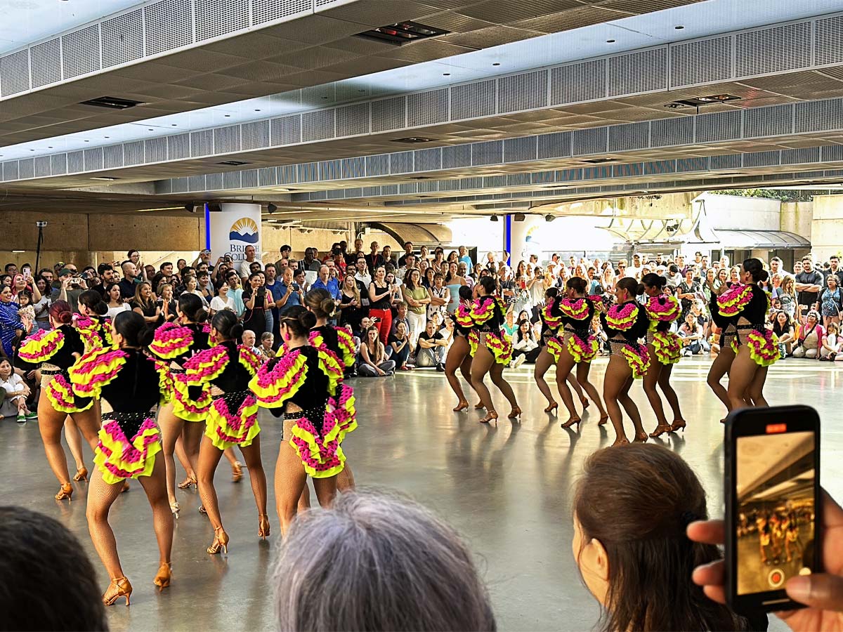 Colorful Latin dance performance drawing a large crowd at Robson Square.