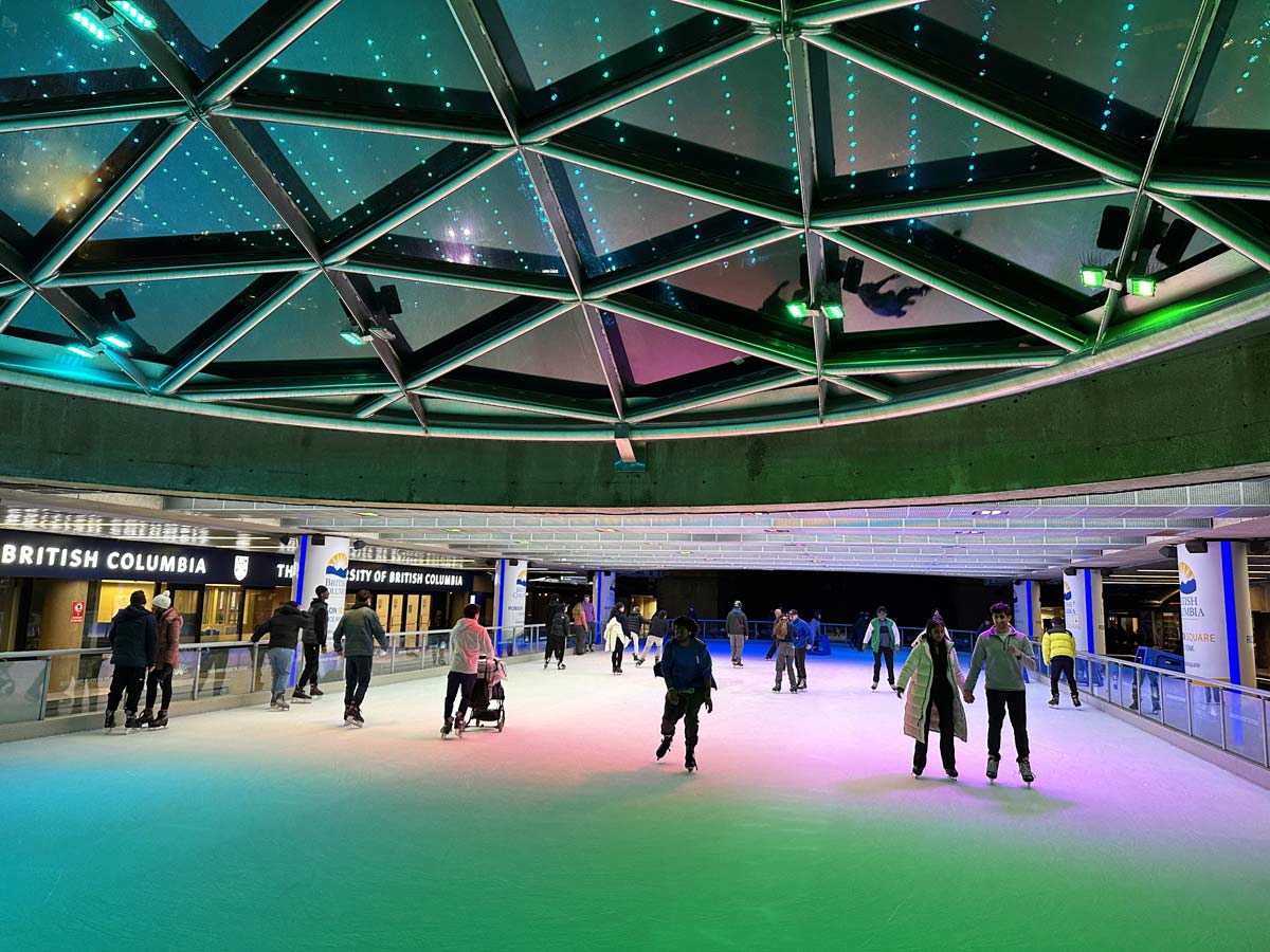 People ice skating under colorful lights at Robson Square rink.