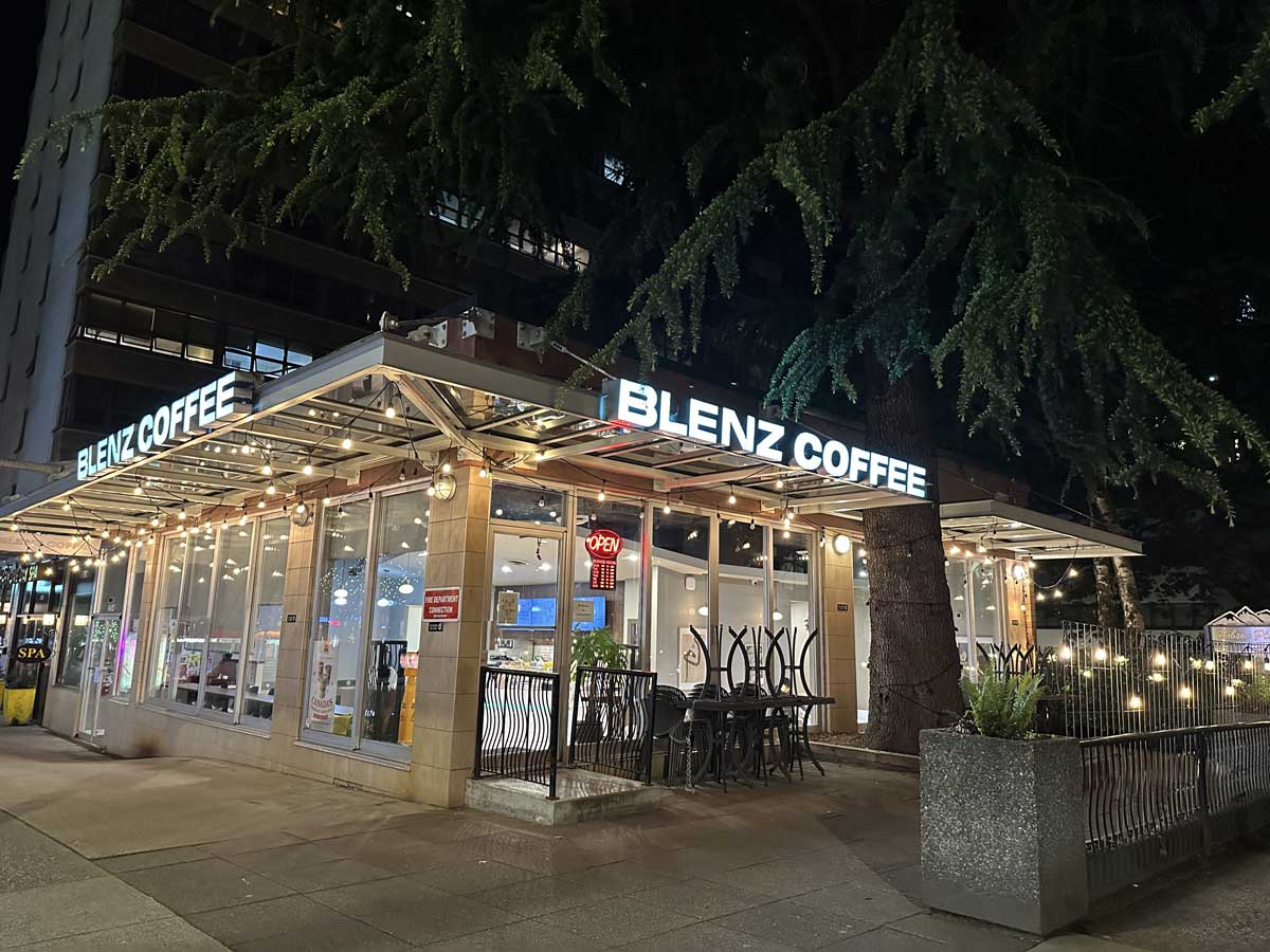 Night view of Blenz exterior with lights & patio seating.