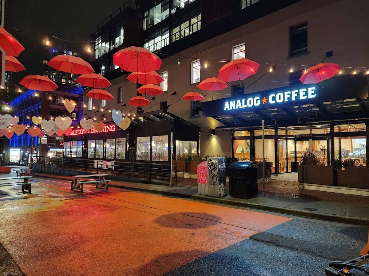 Analog Coffee Yaletown at night under red umbrella lights.
