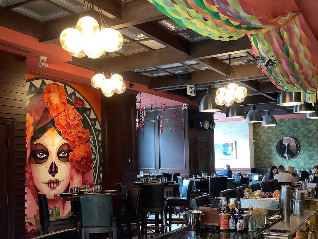 Colorful Mexican-themed dining room with mural and streamers.