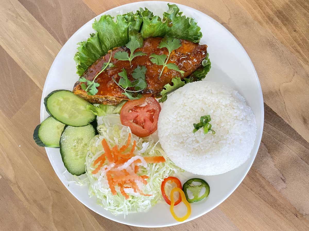 Grilled fish with rice, fresh vegetables, and pickled salad.