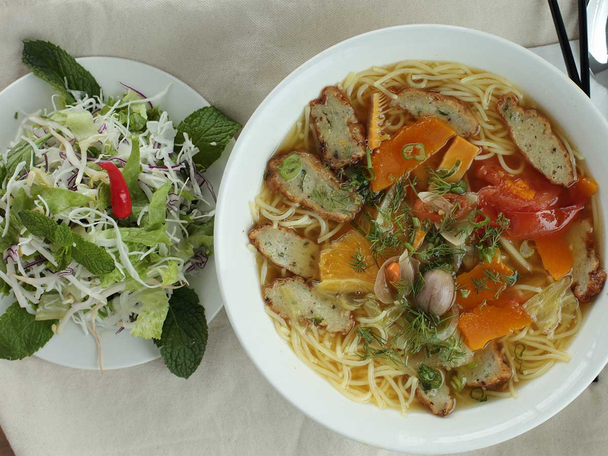 Fish cake vermicelli soup with fresh herbs and vegetables.