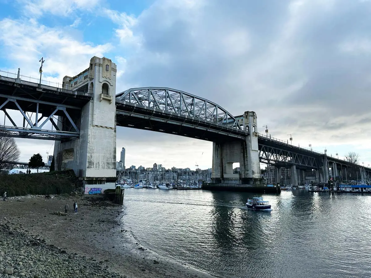 Burrard Bridge in Vancouver spanning False Creek, featuring Art Deco towers, waterfront marina, and city skyline in the background.