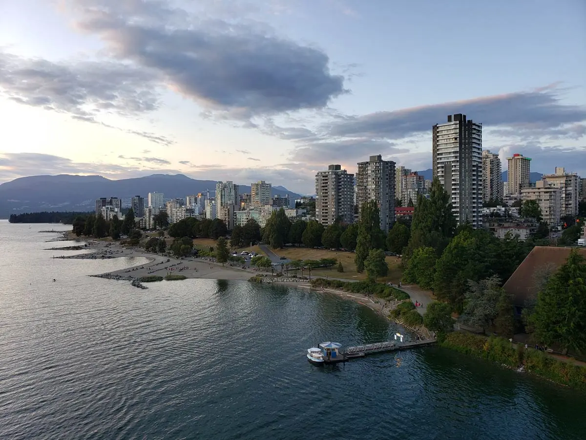 Aerial view of Sunset Beach in Vancouver with city skyline and mountains at dusk.