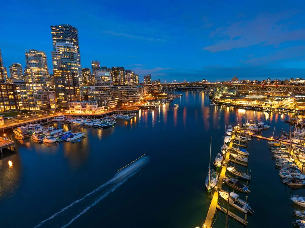 Night view of Granville Bridge, Vancouver skyline, and marina from Burrard Bridge, with city lights reflecting on False Creek.