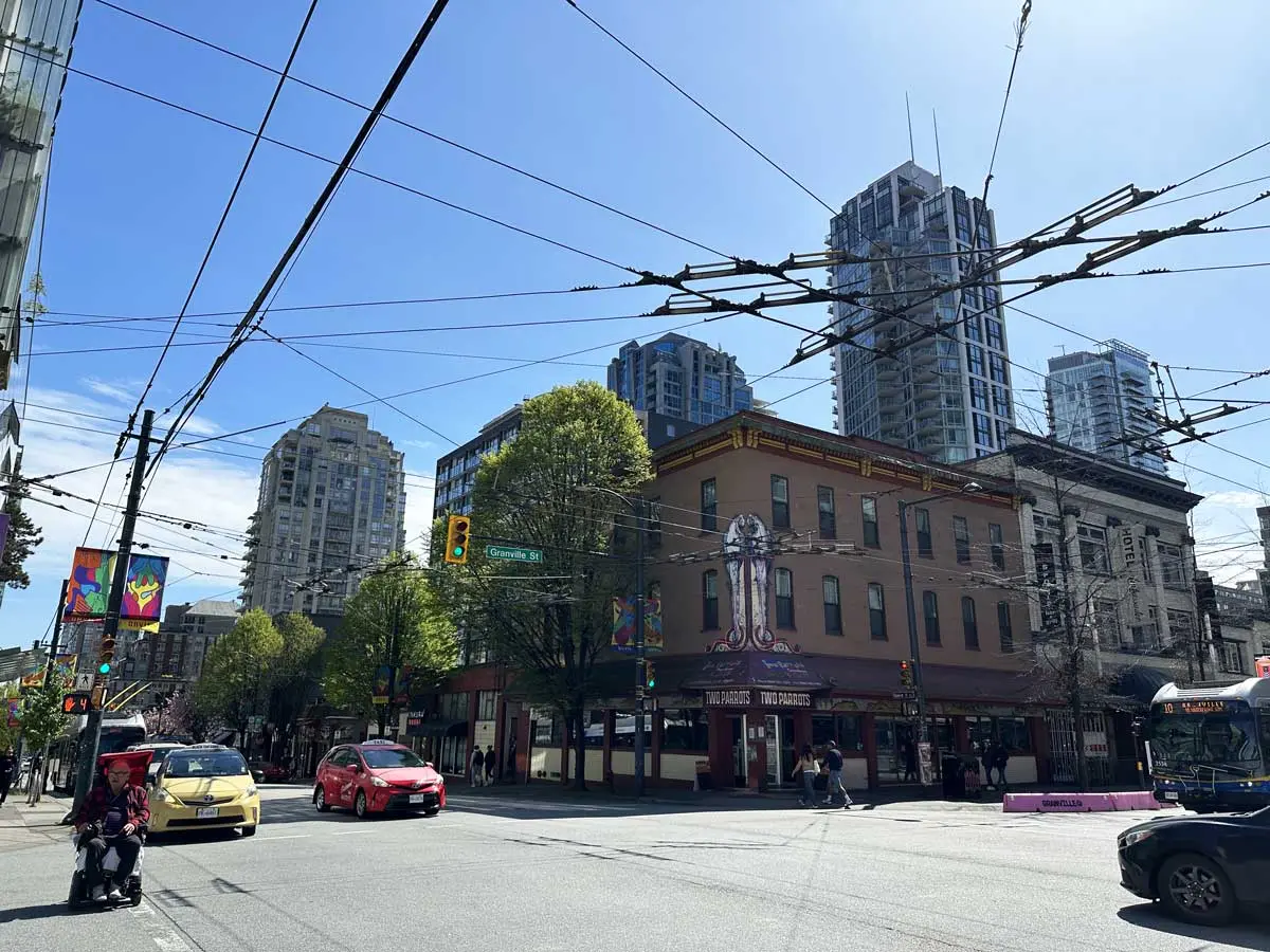 Intersection of Davie and Granville Street with traffic, transit wires, and downtown Vancouver buildings in view.