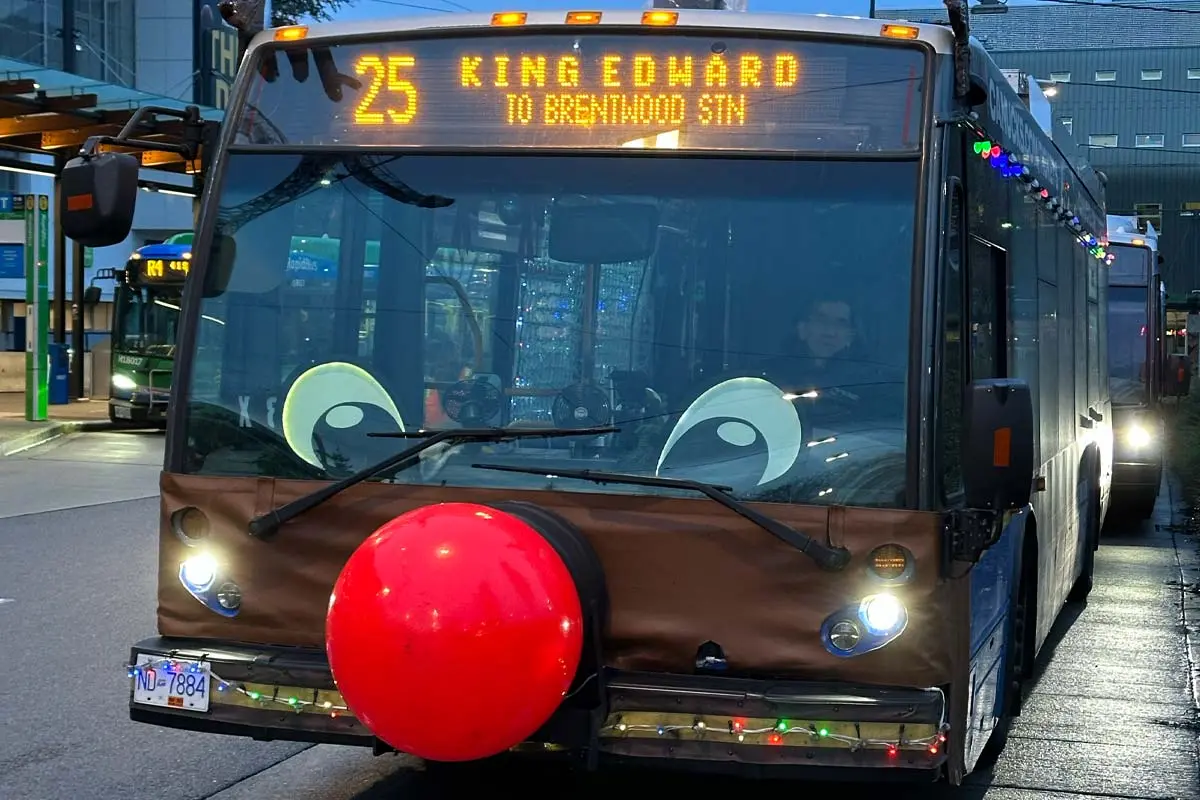 Bus decorated like Rudolph with a red nose and Christmas lights at a Vancouver transit station.