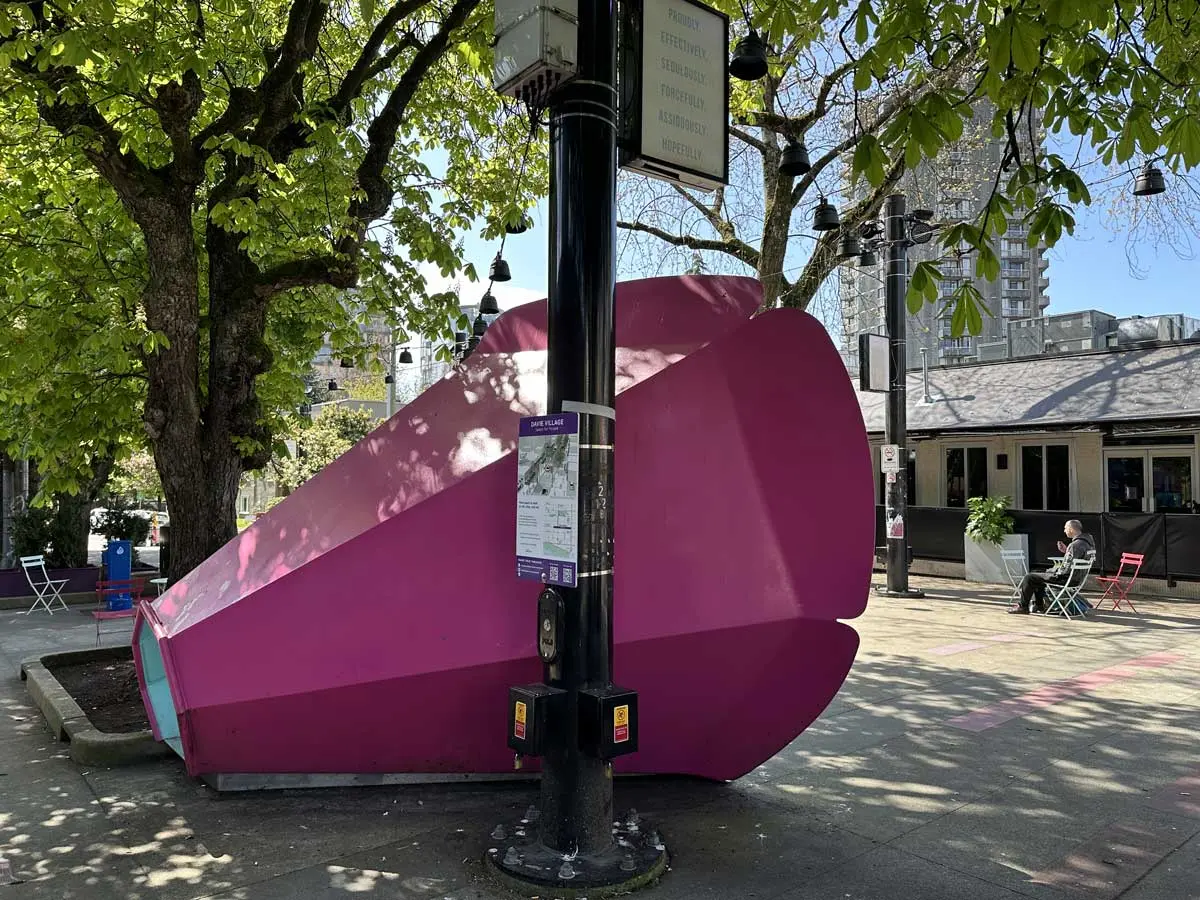 Large pink megaphone sculpture at Jim Deva Plaza surrounded by trees and outdoor seating in Vancouver.