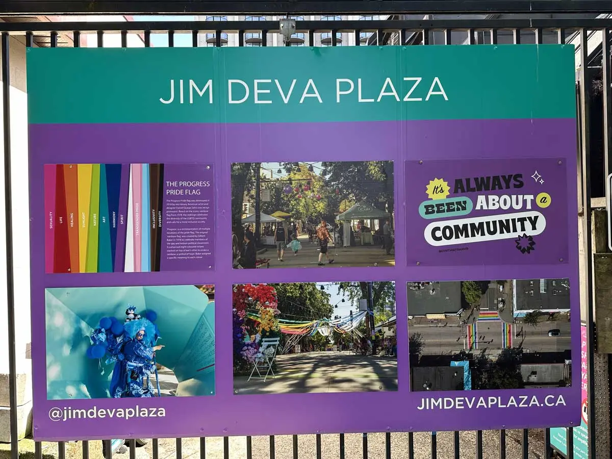 Colorful signboard at Jim Deva Plaza featuring photos, the Progress Pride Flag, and a message about community.