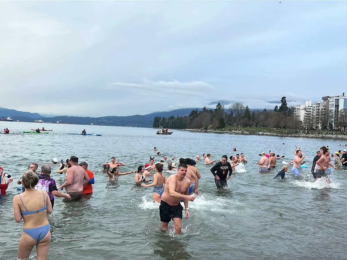 People splashing and swimming in cold water at the Polar Bear Swim in Vancouver.