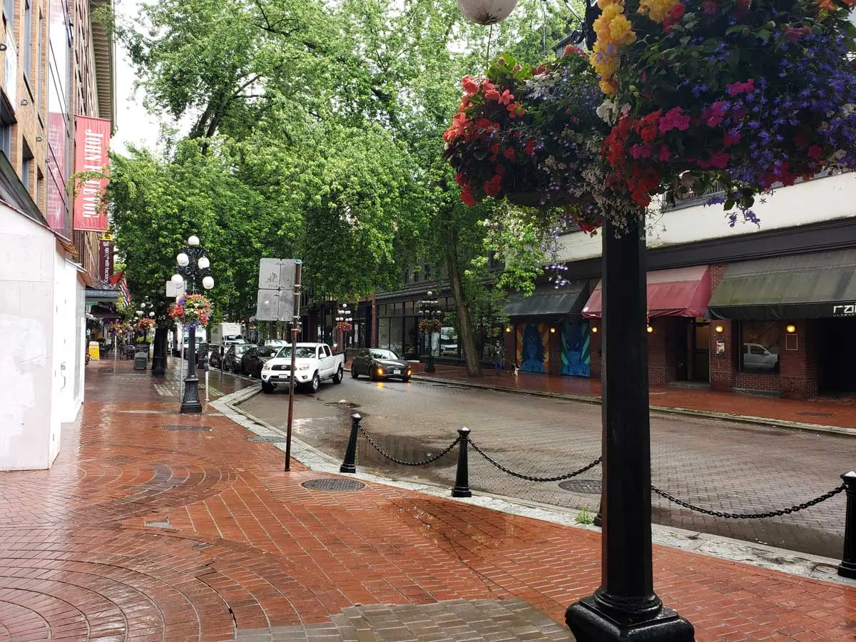 Rainy day in Gastown with wet brick streets and hanging flower baskets.