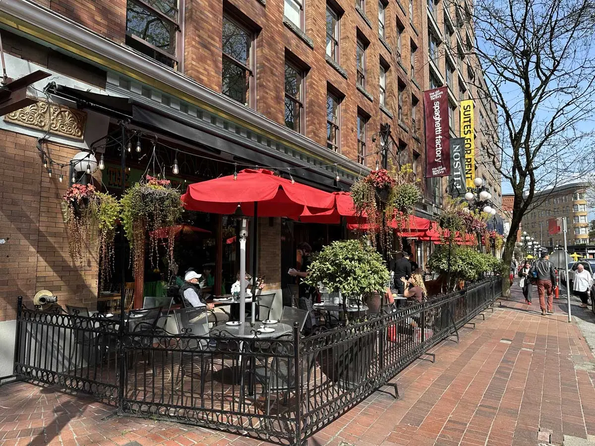 Outdoor dining at Old Spaghetti Factory with red umbrellas in Gastown.