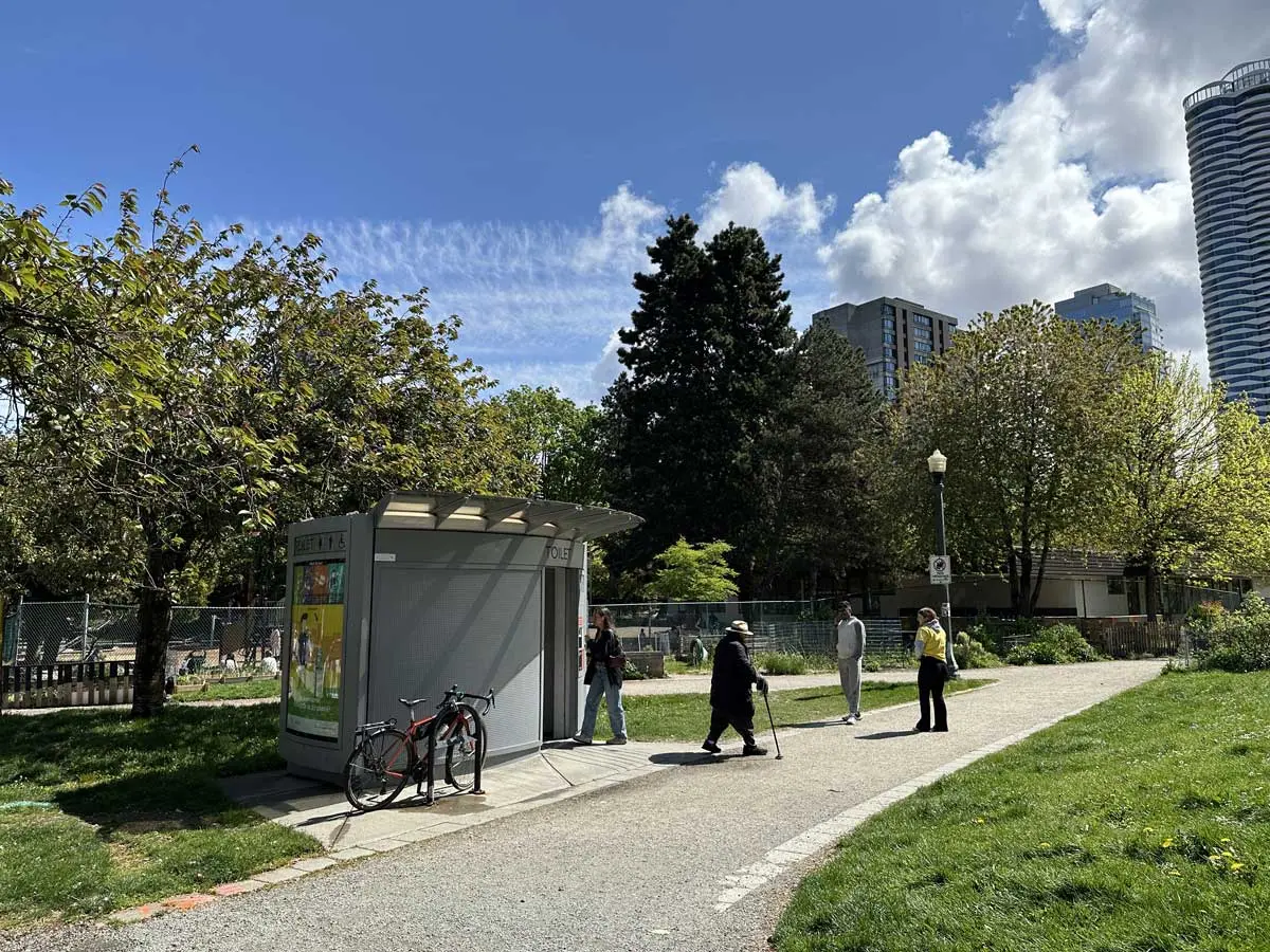 Small public washroom in Nelson Park with people walking nearby.