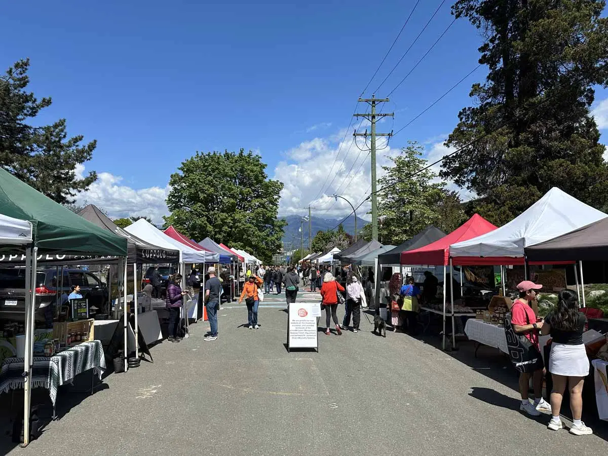 Rows of colorful vendor tents at Mount Pleasant Farmers Market on a sunny day.