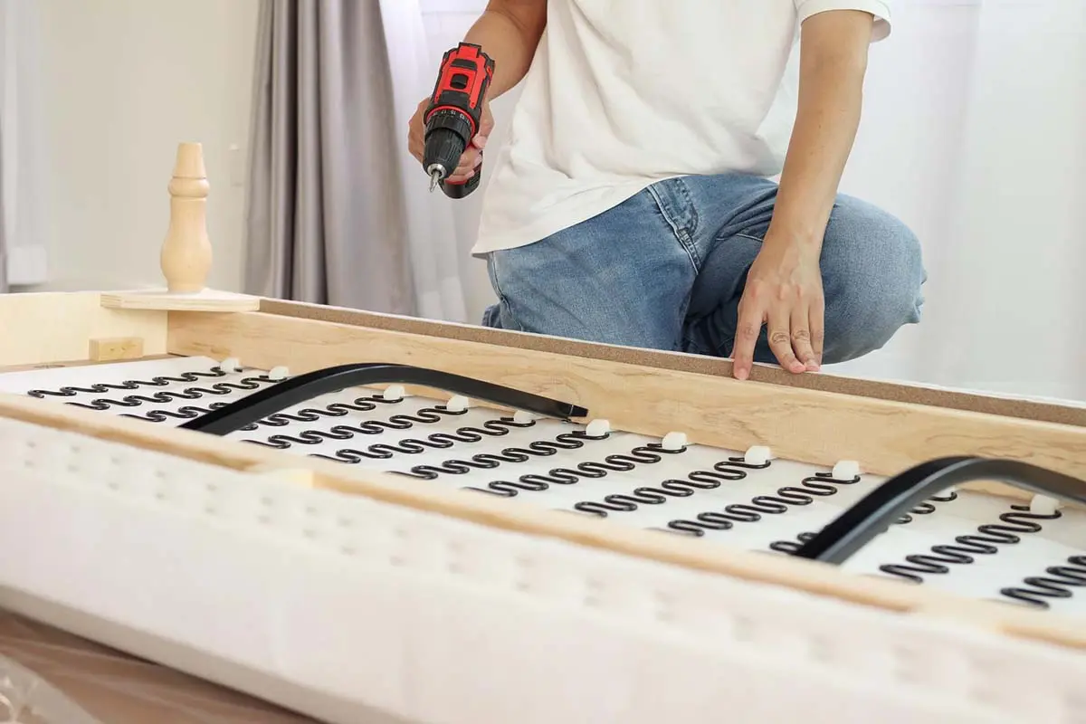 Person using a power drill to assemble a couch frame.