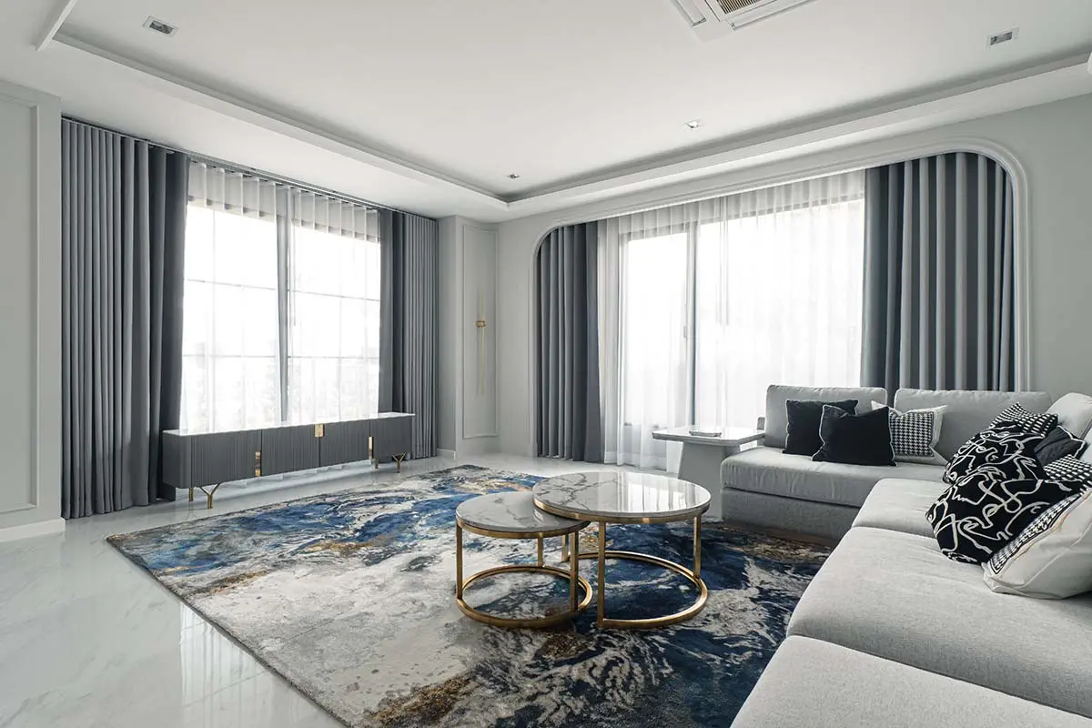 A living room featuring dual gray dimout curtains paired with sheer curtains as the inner layer.