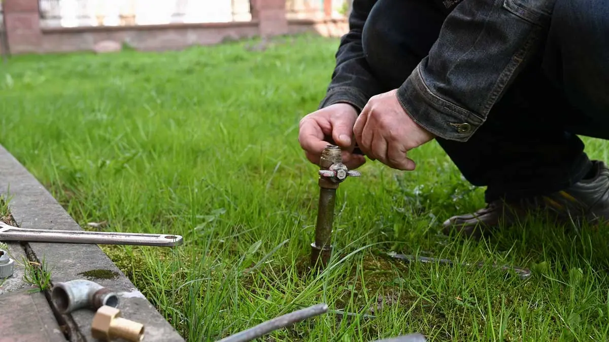 Repairing a garden irrigation pipe with tools on the grass.