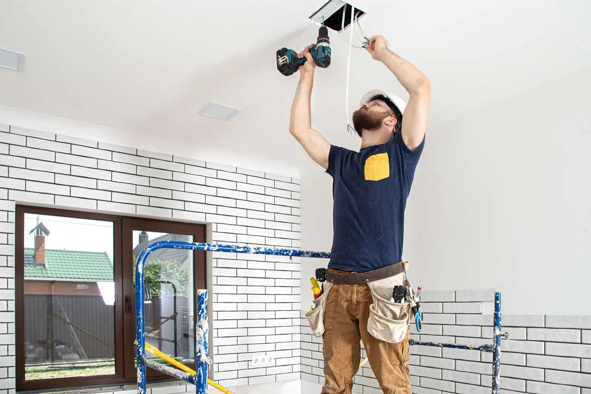 A technician installing motion-activated ceiling lights, enhancing energy efficiency and security for an interior space.