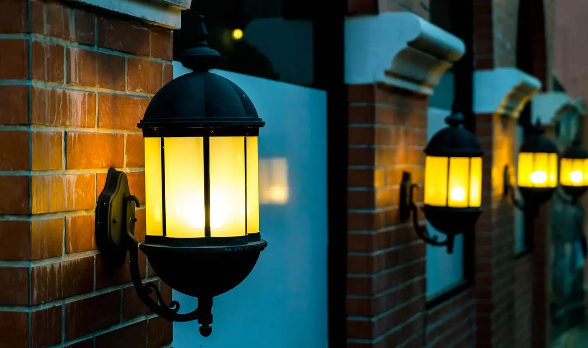 Outdoor wall-mounted lantern-style lights glowing warmly, ideal for motion-activated security and enhancing curb appeal.
