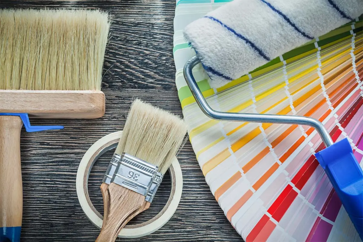 Painting brushes, tape, and a roller with color swatches arranged for color selection.