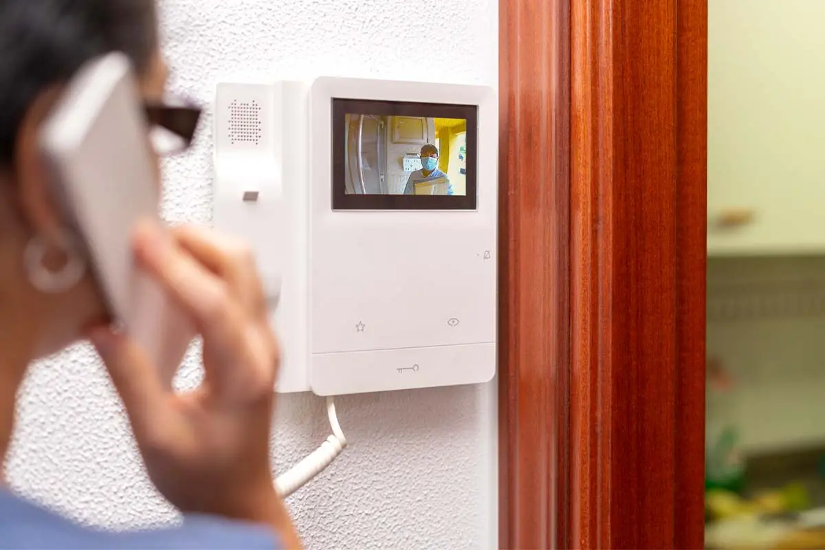 Indoor intercom with video display showing a visitor at the door.