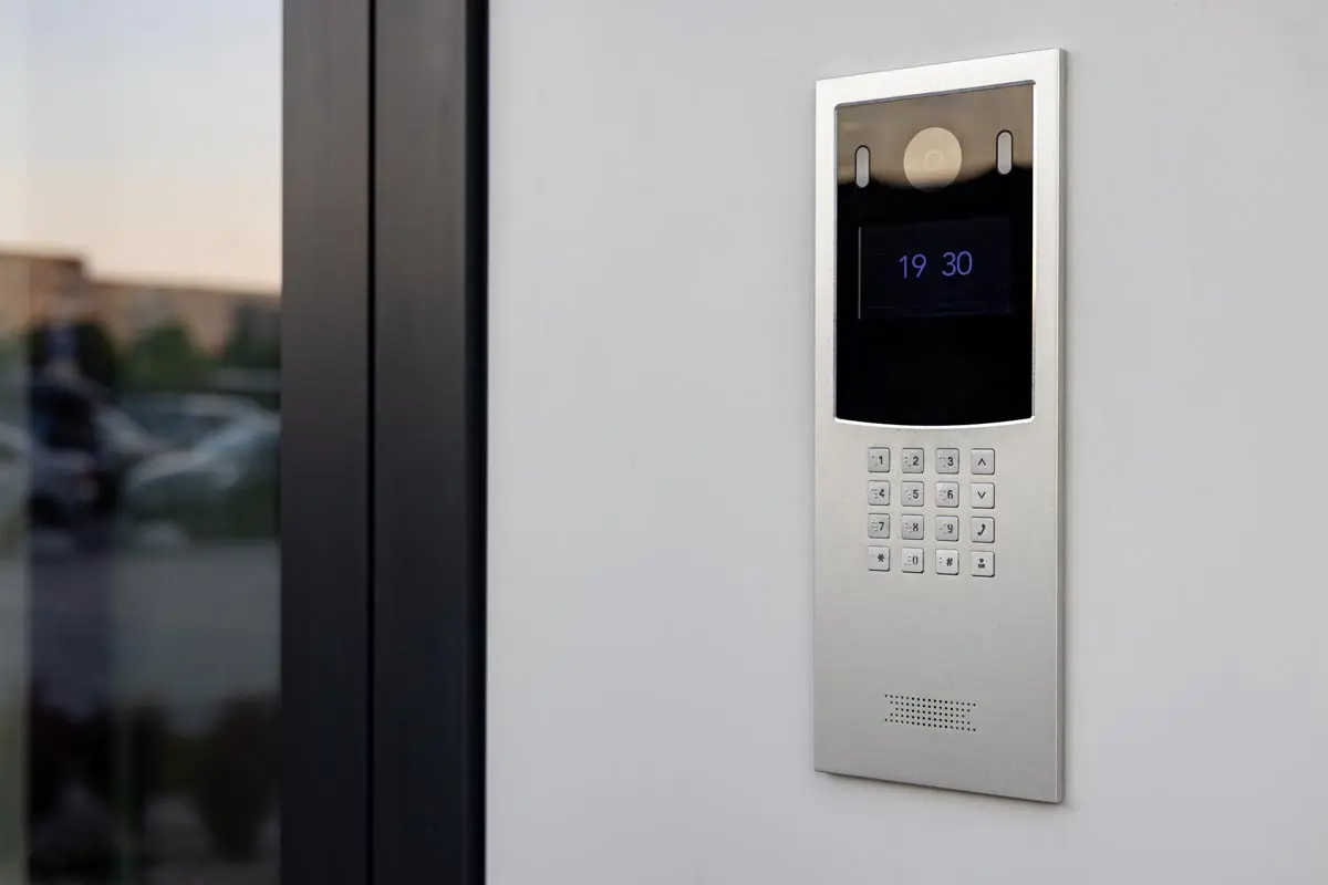 Wall-mounted doorbell with video camera, microphone, and keypad.