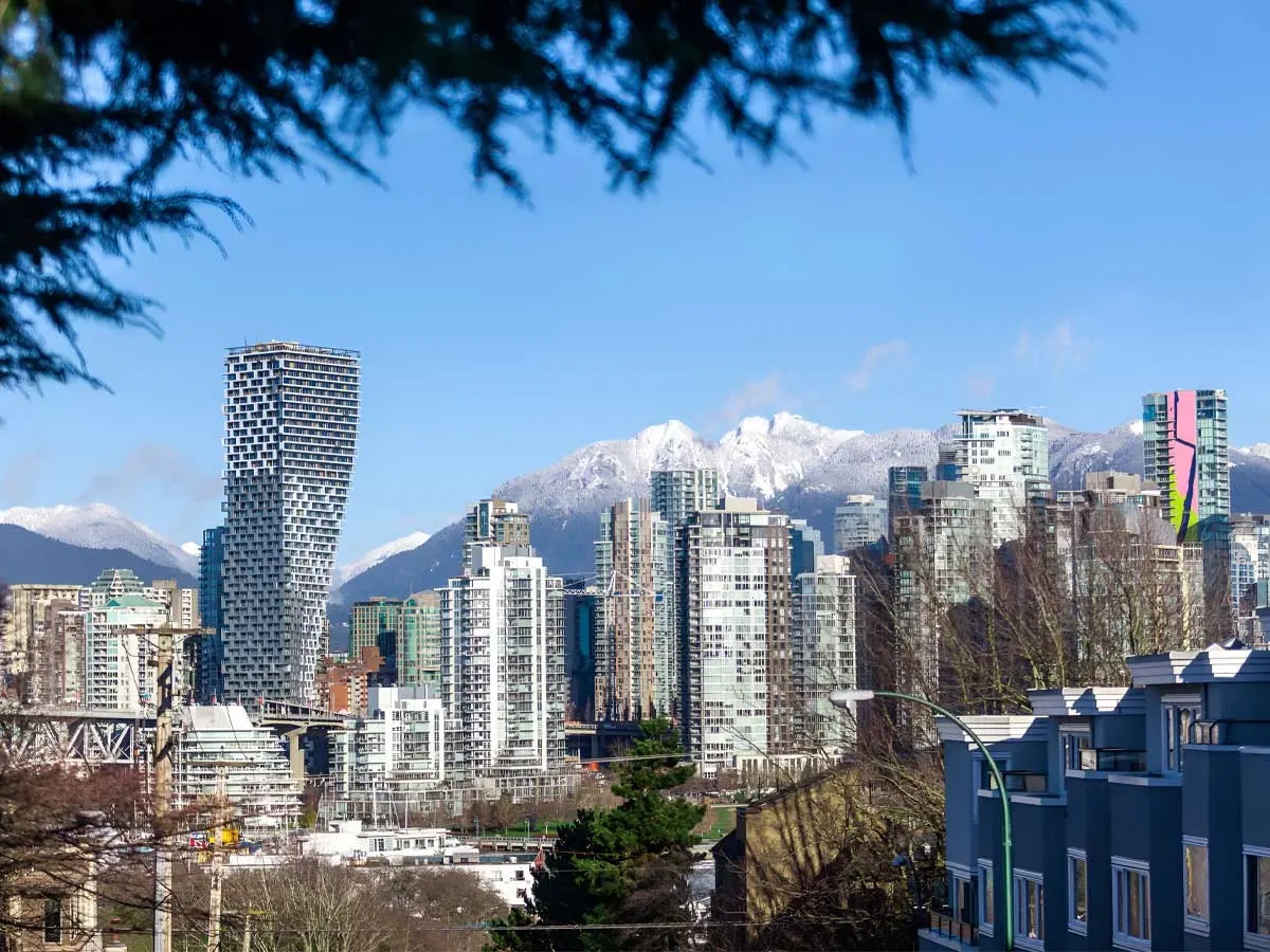 View of downtown Vancouver with modern condos and snow-capped mountains in the background.