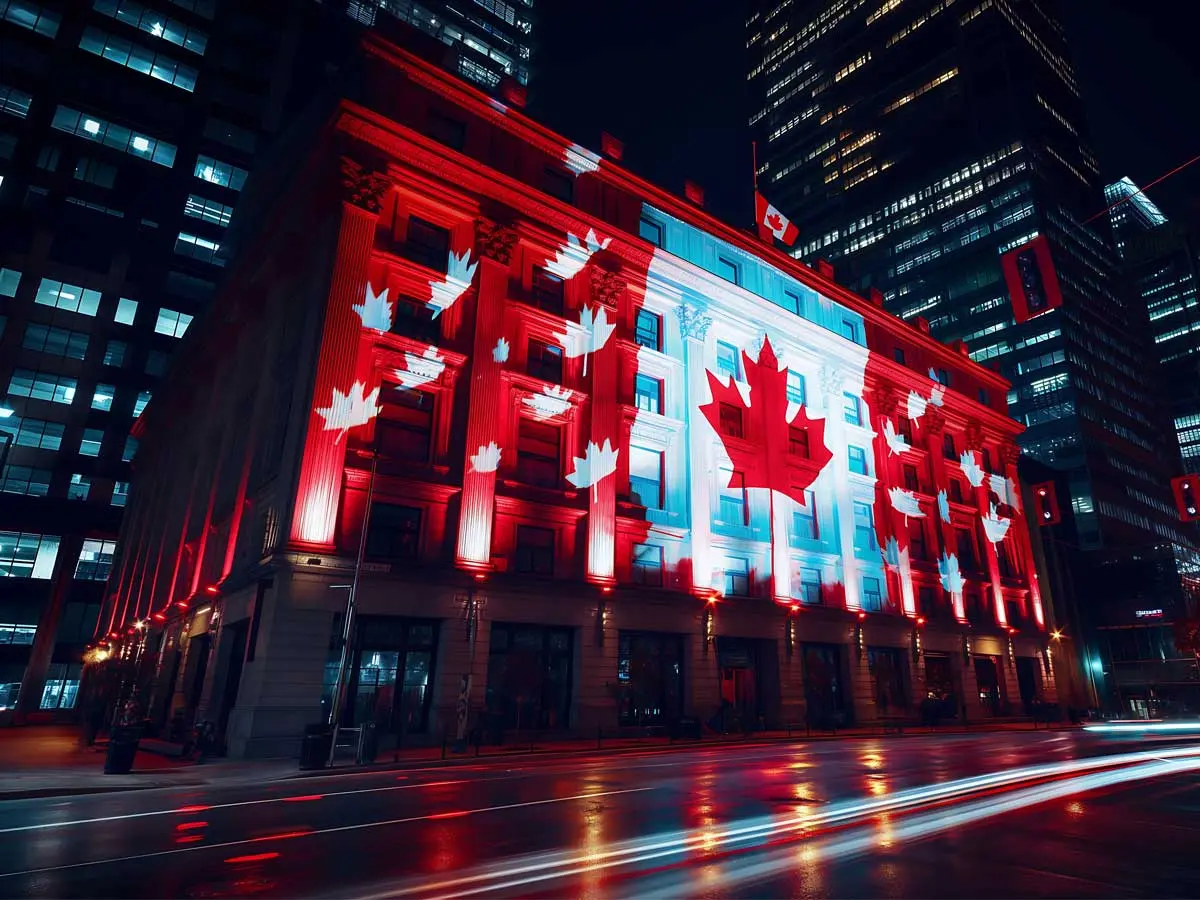 Building in downtown Canada lit up with red and white maple leaf lights at night.