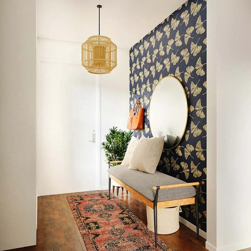 Entryway decorated with botanical wallpaper, a round mirror, bench seating, and a pendant light for a welcoming touch.