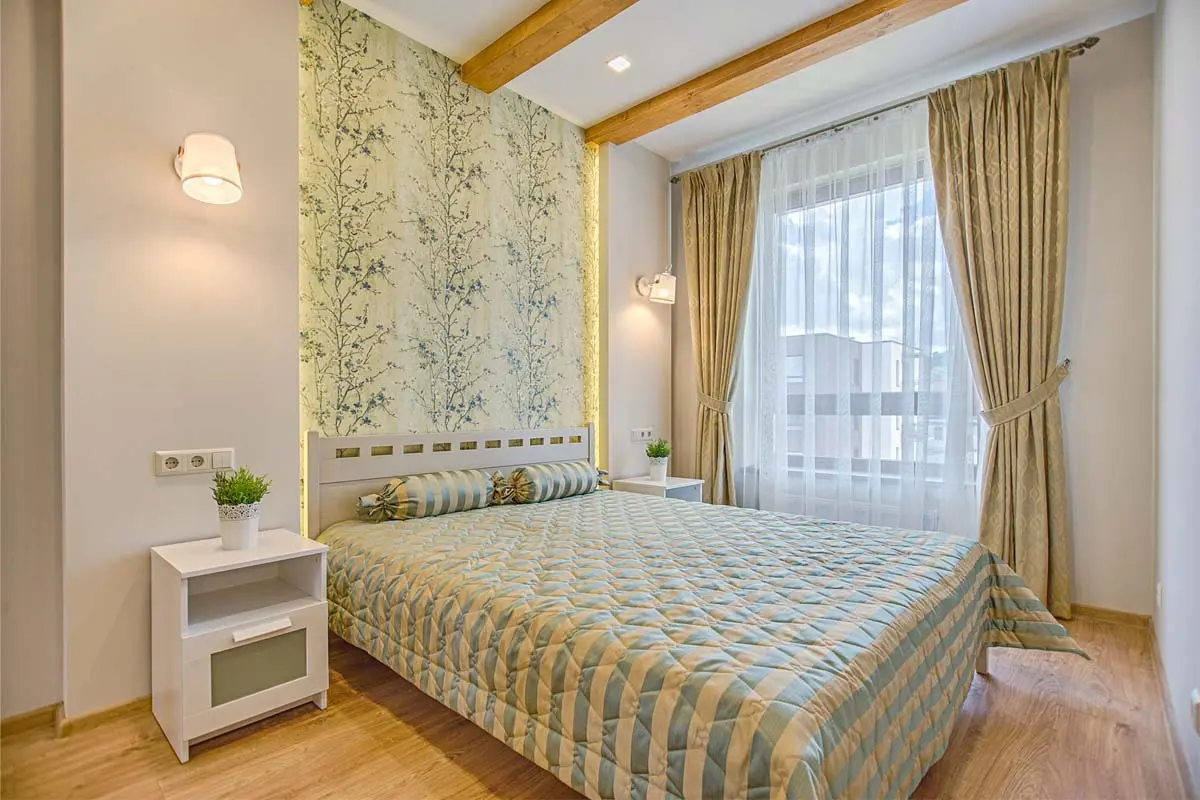 Cozy bedroom featuring botanical accent wallpaper, soft lighting, and coordinated curtains for a serene ambiance.
