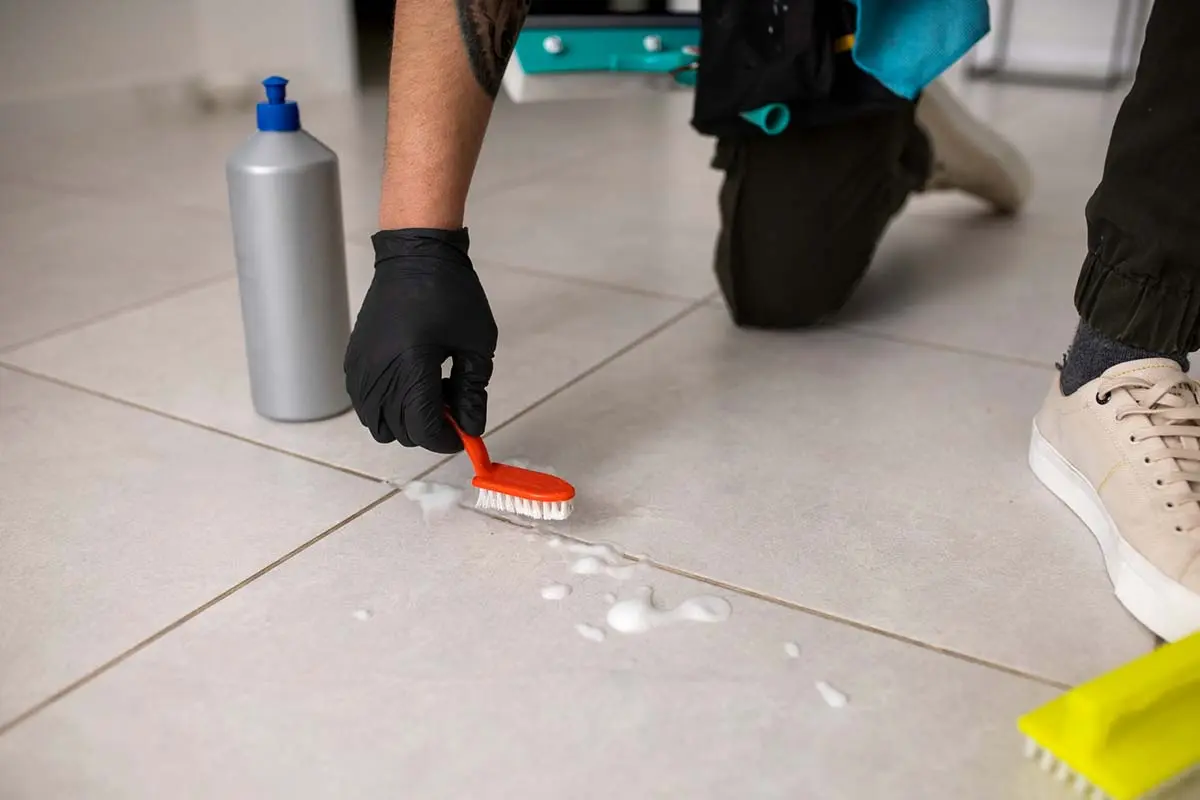 Scrubbing between floor tiles with a brush.