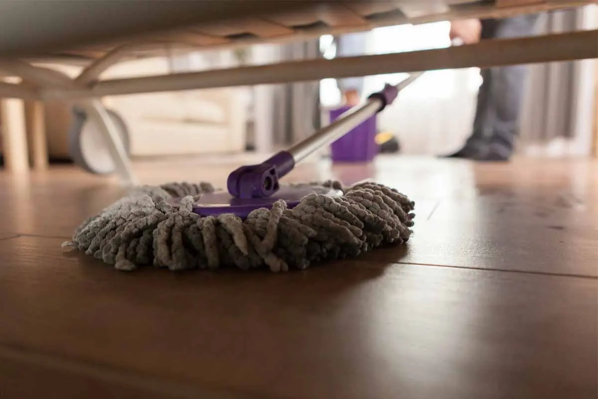 Mopping under furniture with a microfiber mop.